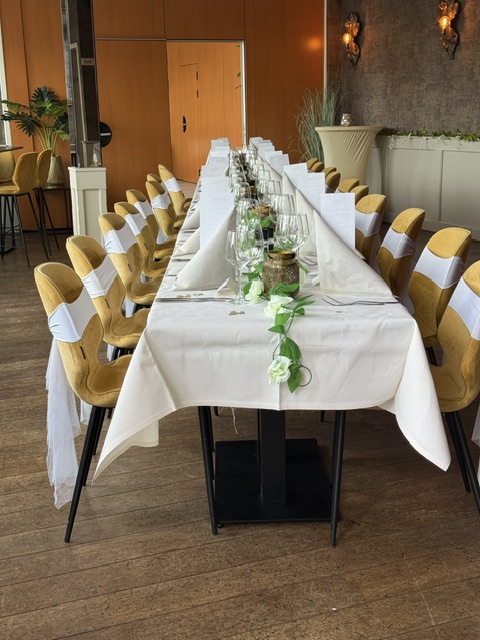 Lange feesttafel met bloemen en gedekte couverts